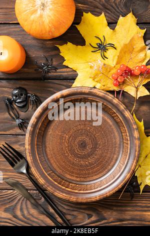 Top view of blank halloween plate with pumpkins on a rustic table. Halloween table setting with cutlery. Festive concept. Stock Photo