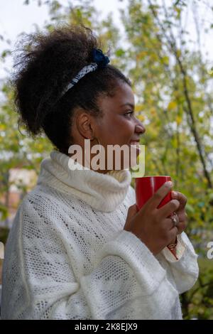 Happy African American woman enjoying a cup of coffee and looking out of window Stock Photo