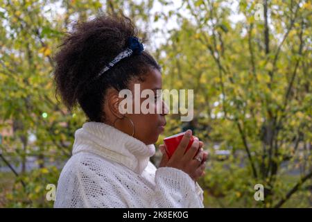 Thoughtful African American woman enjoying a cup of  tea and looking out the window Stock Photo