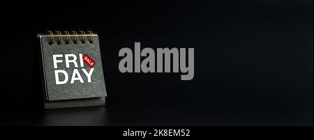 Black Friday sale concept. BLACK FRIDAY SALE, white text with red tag on small black spiral desk calendar cover standing on dark banner background wit Stock Photo