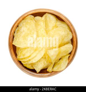 Salted potato chips, crisps in a wooden bowl. Thin slices of potato, deep fried in oil until crunchy. Served as a snack, side dish or appetizer. Stock Photo