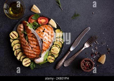 Cooked salmon fish with vegetables on dark background Stock Photo