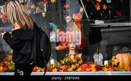 Brighton UK 23rd October 2022 - A visitor passes by a Halloween decorated window at a hair salon on an unusually warm day for the time of year in Brighton today as temperatures are expected to reach 20 degrees in some parts of the South East  . : Credit Simon Dack / Alamy Live News Stock Photo