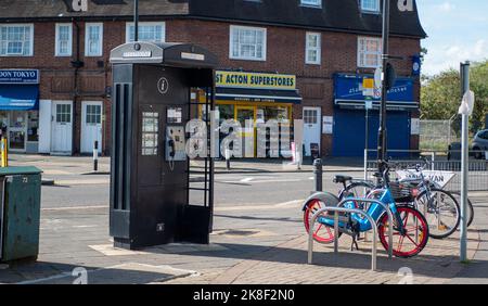 An old-school telephone box near shops in West Acton, London. Stock Photo