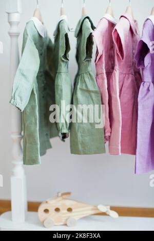 Colorful dresses hanging on rack in front of wall Stock Photo