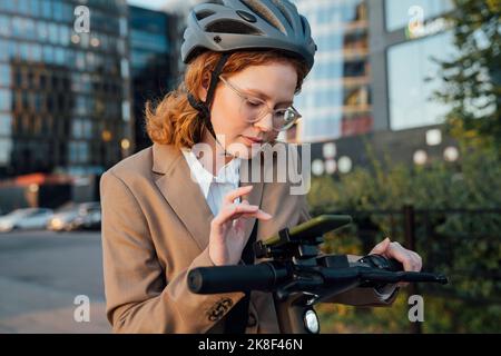 Young businesswoman using smart phone on electric push scooter Stock Photo
