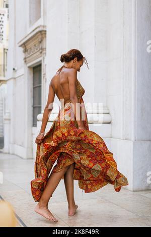 Young woman wearing summer dress walking in front of building Stock Photo