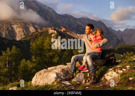 Girl looking through binoculars sitting on Father's lap Stock Photo