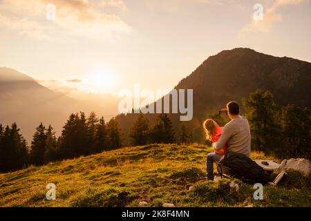 Mature man with daughter taking selfie through smart phone sitting on bench Stock Photo