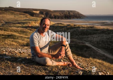 Contemplative mature man sitting on hill Stock Photo
