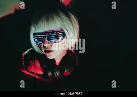 Woman with white short hair wearing neon glasses against black background Stock Photo