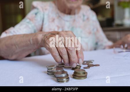 Senior woman stacking coins on table at home Stock Photo