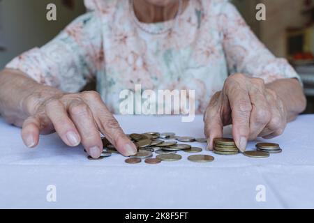 Senior woman stacking coins on table at home Stock Photo