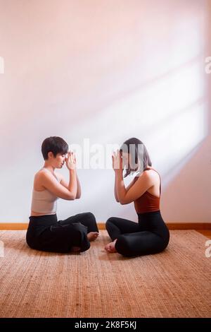 Friends practicing yoga together in front of each other Stock Photo