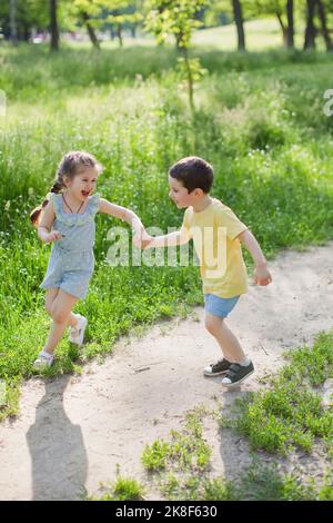 Cheerful cute girl playing with brother at park Stock Photo