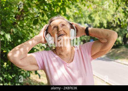Happy senior woman listening to music and exercising in park Stock Photo