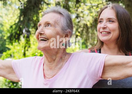 Happy senior woman with fitness instructor exercising at park Stock Photo