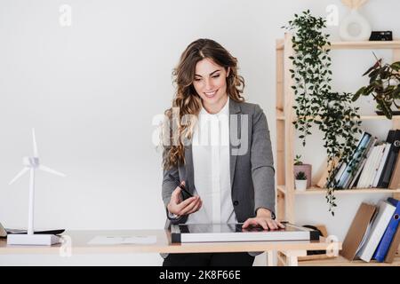 Modern businesswoman with smartphone using portable solar module in office Stock Photo