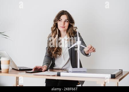 Female engineer working in modern office holding windturbine model Stock Photo