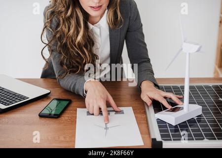 Female engineer working on windturbine model using smartphone Stock Photo