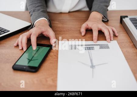 Female engineer working on windturbine model using smartphone Stock Photo