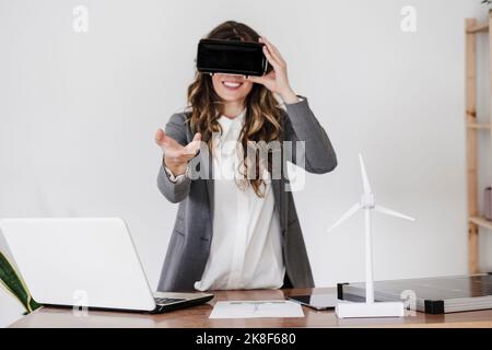 Gesturing young businesswoman using virtual reality simultor in office Stock Photo