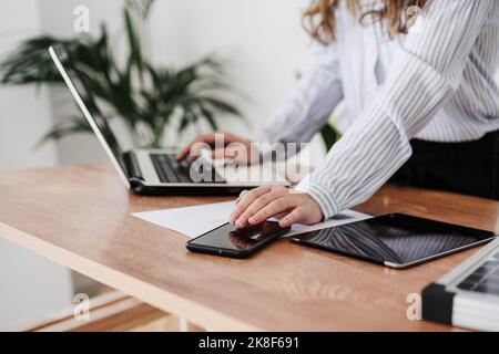 Young businesswoman working in modern office using laptop and smartphone. close up Stock Photo