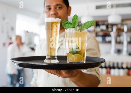 Waiter with tray serving drinks at restaurant Stock Photo