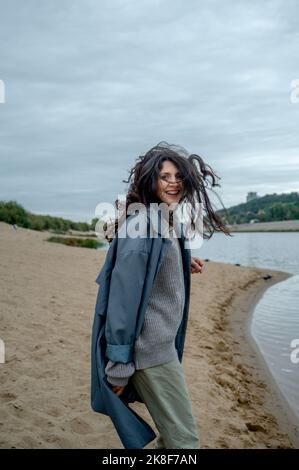 Playful woman wearing raincoat at shore Stock Photo