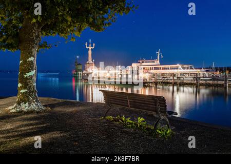 Germany, Baden-Wurttemberg, Konstanz, Harbor on shore of Lake Constance at night with empty bench in foreground Stock Photo