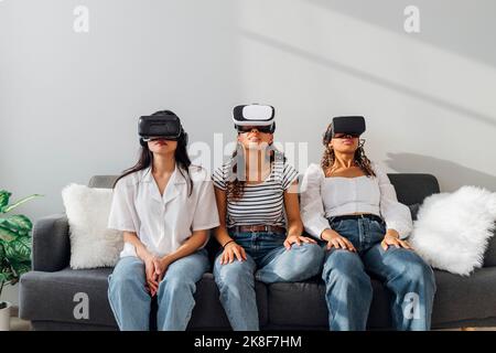 Young roommates watching through VR glasses at home Stock Photo