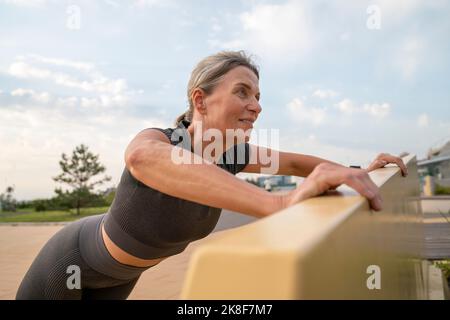 Mature woman doing push-ups on bench Stock Photo