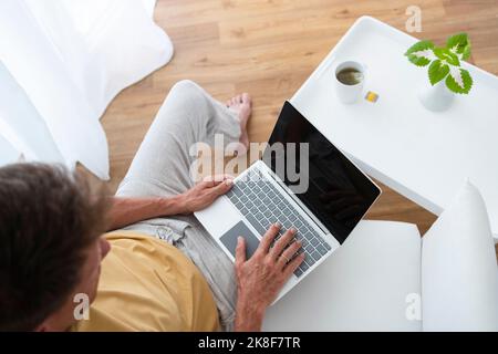 Freelancer working on laptop sitting at home Stock Photo