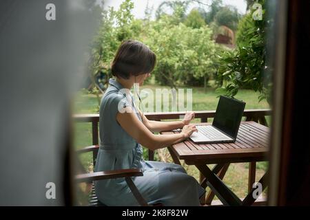 Freelancer using laptop sitting on balcony Stock Photo
