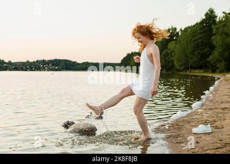 Happy woman splashing water at beach Stock Photo