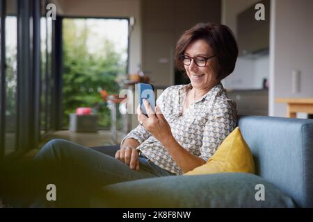 Happy senior woman using smart phone at home Stock Photo