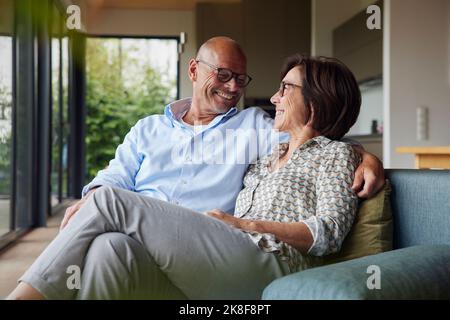 Loving senior couple sitting on sofa at home Stock Photo
