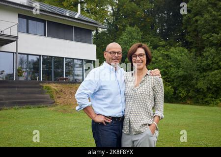 Happy senior man and woman standing together in front yard Stock Photo