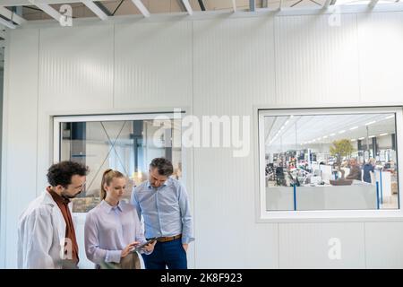 Manager discussing over tablet PC to colleagues in factory Stock Photo