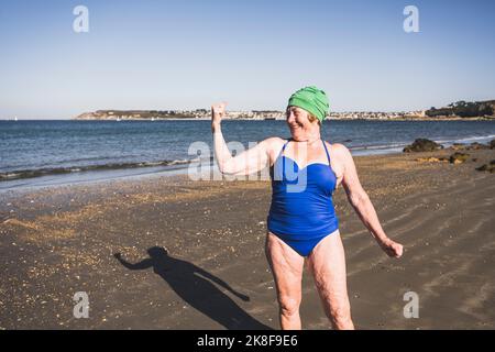 Woman showing biceps at beach on sunny day Stock Photo