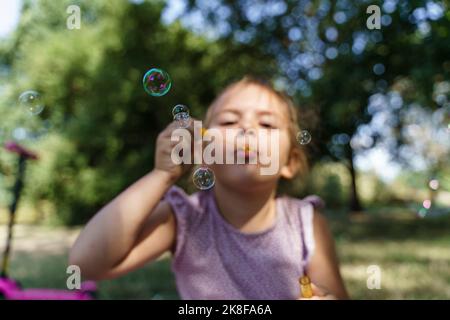 Girl blowing soap bubbles in park Stock Photo
