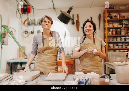 Happy entrepreneur with colleague working together at ceramics workshop Stock Photo