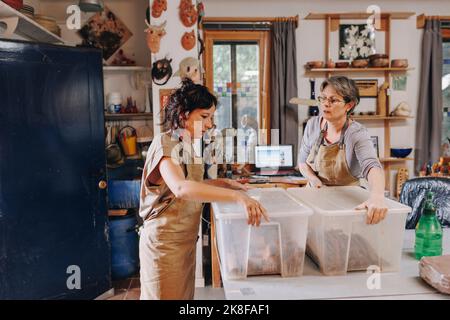 Entrepreneur with colleague holding plastic containers at ceramics workshop Stock Photo