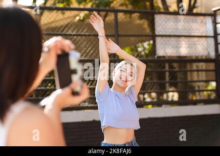 Woman photographing friend through camera on sunny day Stock Photo