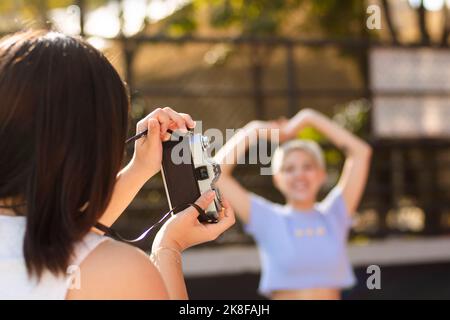 Young woman photographing friend through camera on sunny day Stock Photo