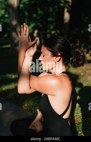 Yoga teacher with eyes closed exercising vajrasana garudasana posture in park Stock Photo