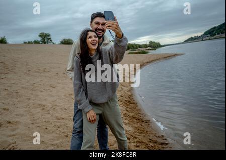 Happy couple having fun taking selfie through smart phone by river Stock Photo