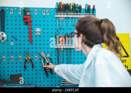 Technician removing work tool from rack in workshop Stock Photo