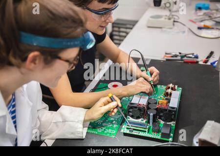 Female technicians soldering motherboard on table in workshop Stock Photo