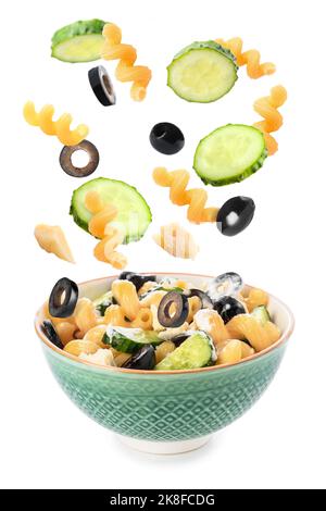 Bowl with delicious pasta salad and falling ingredients on white background Stock Photo